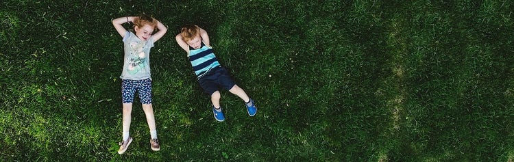 A child lying on his back on grass Description automatically generated