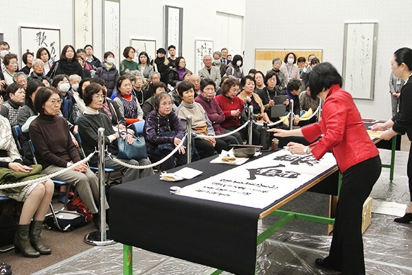 日書展会場で席上揮毫をする荒井先生と、観客の皆さん1