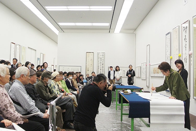 第70回日書展の会場にて大勢の観客が見守る中、席上揮毫をされる名和さん1