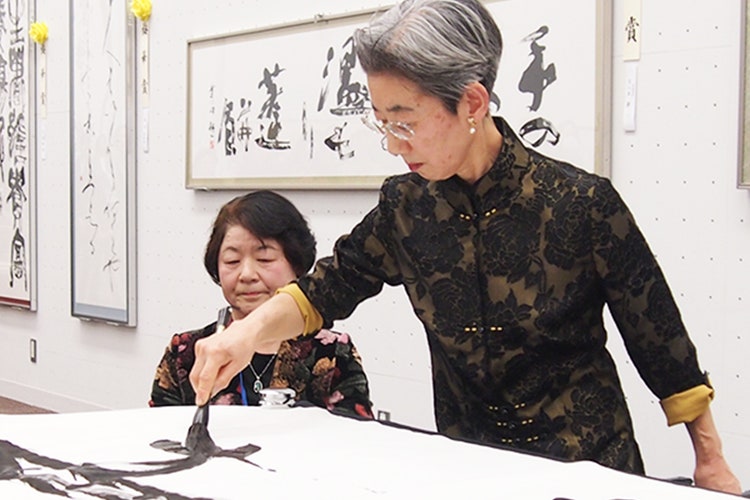 日書展会場で席上揮毫をする浅田先生と、観客の皆さん2