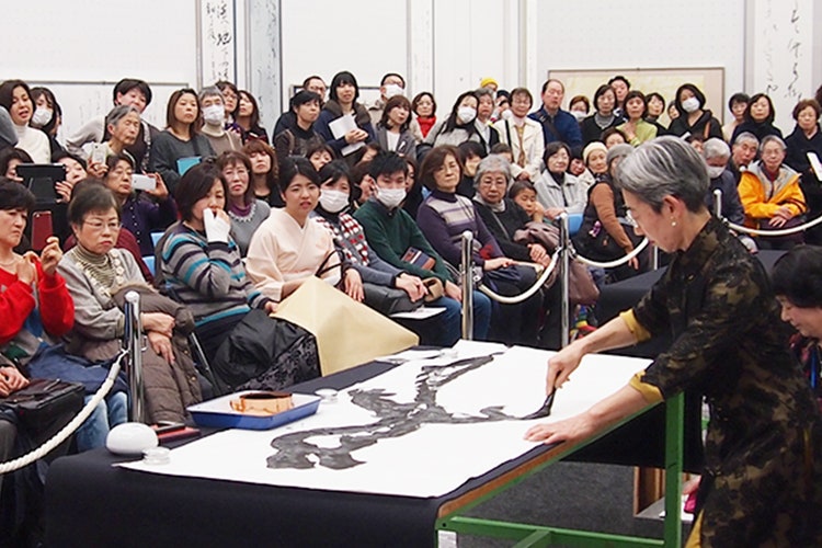 日書展会場で席上揮毫をする浅田先生と、観客の皆さん1