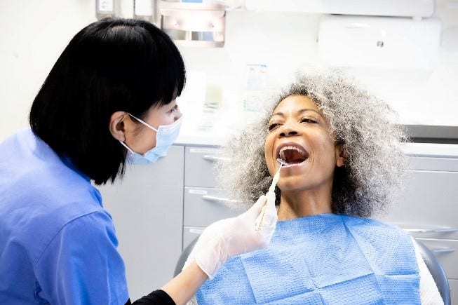 Dentist applying Sunstar professional oral care product to patient during treatment.